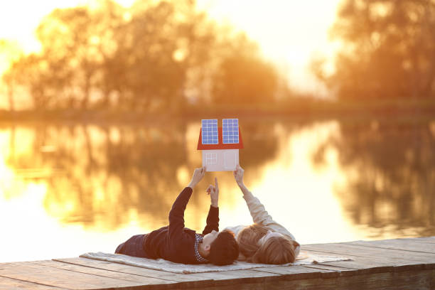 felice coppia di bambini che sognano una casa con pannelli solari - alternative enregy foto e immagini stock