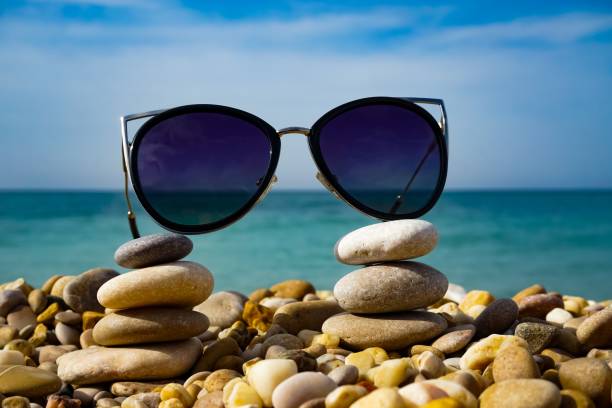 солнцезащитные очки лежат на морской гальке на фоне моря и неба в солнечный день - 44902 стоковые фото и изображения