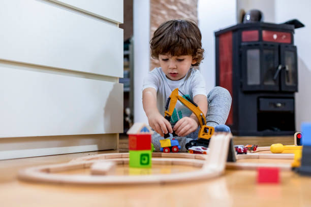 istock Beautiful little boy playing with a railroad train toy and plastic vehicle. 1283250966