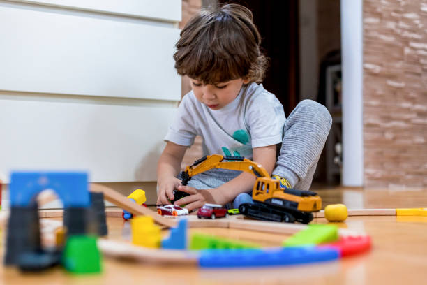 istock Beautiful little boy playing with a railroad train toy and plastic vehicle. 1283250979