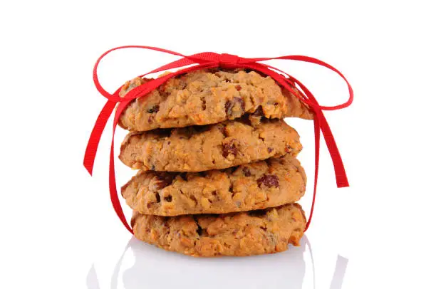 Closeup of a stack of Oatmeal Raisin Cookies tied up with a red ribbon, isolated on white.