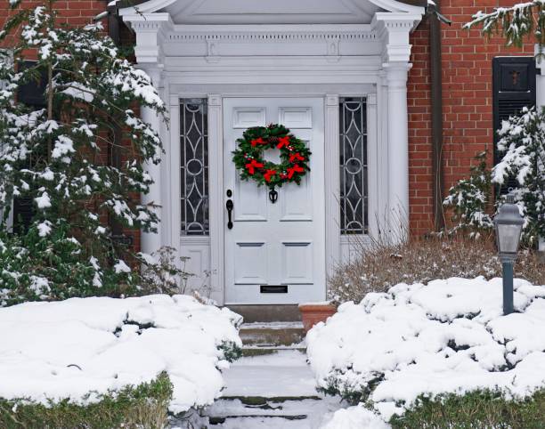 눈 덮인 상록 관목이있는 집의 크리스마스 화환이있는 나무 현관 문 - wreath christmas door snow 뉴스 사진 이미지