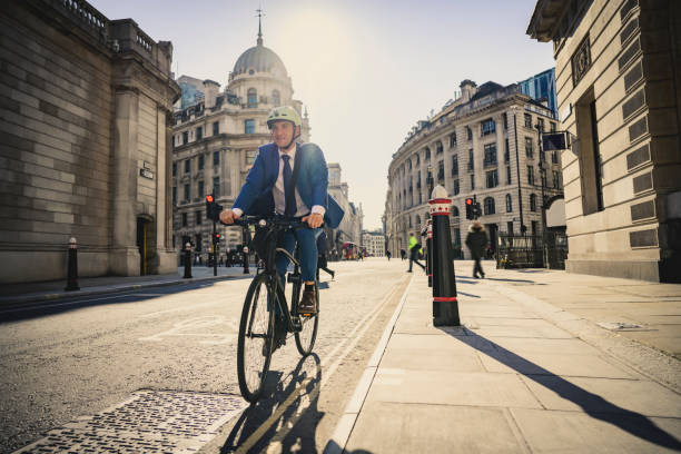 britische exekutive genießt sonnige fahrt zur arbeit mit dem fahrrad - front view bus photography day stock-fotos und bilder
