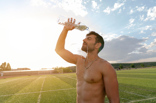 Tired Athletic Man With Muscular Body Pouring Water Over Face, Resting After Running Workout.