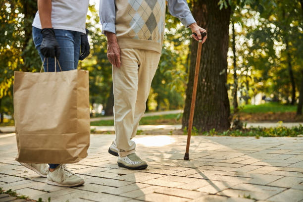 istock Senior man with crutch and female helping with purchase 1283263658