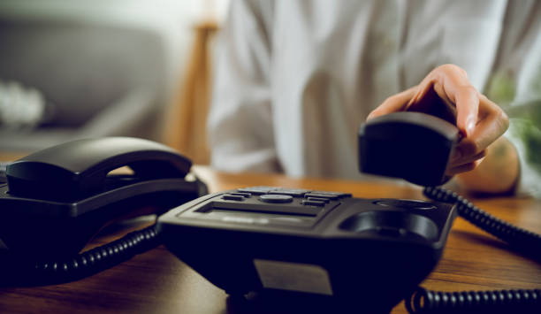 istock close up hand holding black landline on the table in office. 1283264300