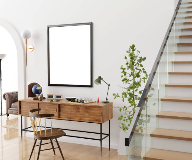 Stylish and eclectic dining room interior with mock up poster map, sharing table design chairs, gold pedant lamp and elegant sofa in second space. White walls, wooden parquet. Tropical leafs in vase.
