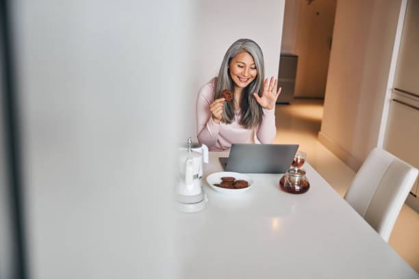 istock Cheerful woman using laptop for online communication during breakfast 1283267846