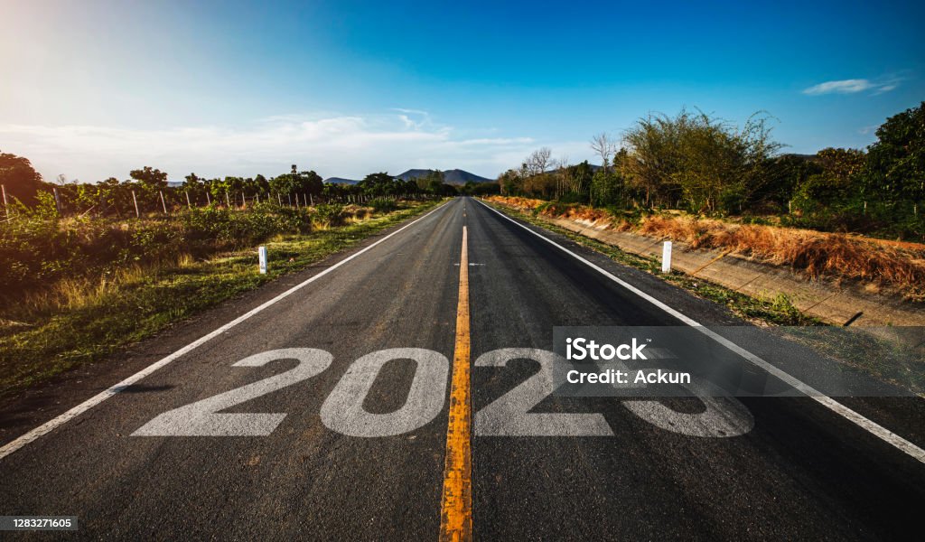 The word 2025 written on highway road in the middle of empty asphalt road golden sunset and beautiful blue sky. Concept for new year 2025. 2025 Stock Photo