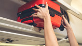 Cabin crew lift luggage bag in airplane