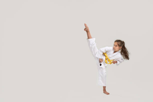 흰색 띠 운동과 싸움, 무술을하고, 흰색 배경 위에 고립 된 서 흰색 기모노에 작은 가라데 소녀의 전체 길이 샷 - karate kicking tae kwon do martial 뉴스 사진 이미지