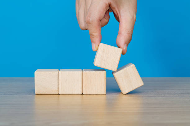 Stack of wood cubes built as step stairs pyramid on white background, wooden toy, permanent, and strong success