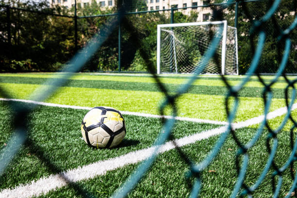 football dans un terrain de football séparé par des barbelés - green fence chainlink fence wall photos et images de collection