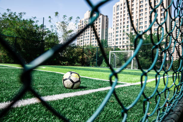 football dans un terrain de football séparé par des barbelés - green fence chainlink fence wall photos et images de collection