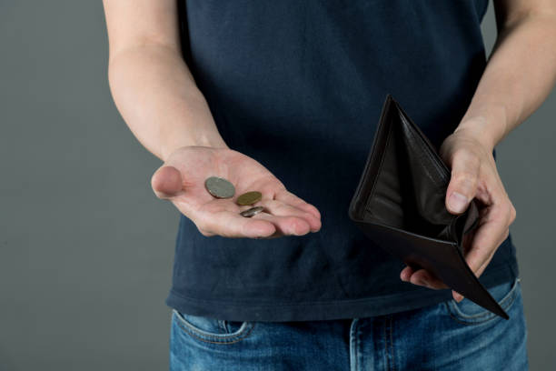 Man holding an empty wallet and few coins