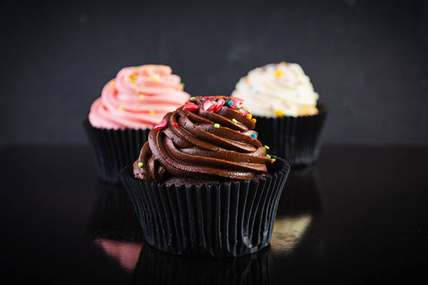 istock Tasty colorful cupcakes isolated on dark background. Delicious cupcake 1283300701