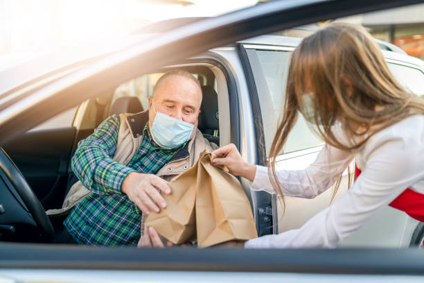 istock Order Being Passed Between  Hands Through Car Window Outside Restaurant During Covid-19 Lockdown 1283300750