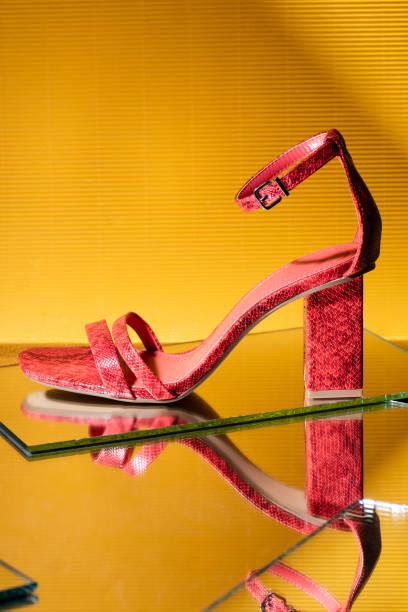 istock elegant red snakeskin heeled sandals on mirror surface on yellow background 1283302974