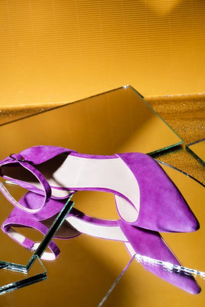 istock elegant violet suede heeled shoe on mirror surface on yellow background 1283302977