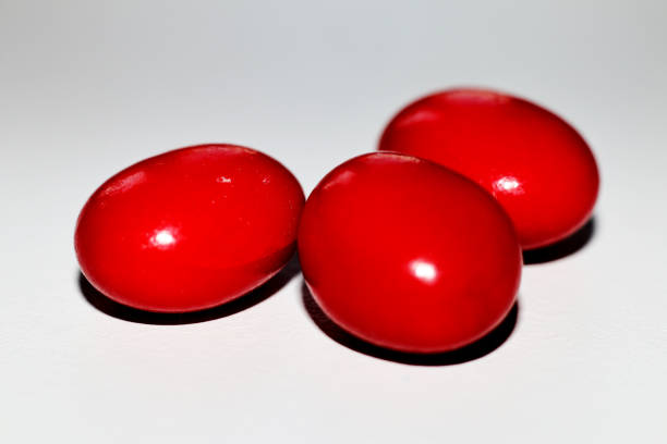 istock Red shiny candies on a white background - extreme close up 1283303275