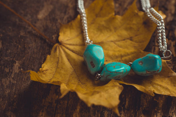 Turquoise stone jewelry on yellow maple leaf