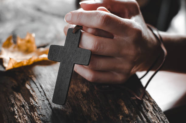 las manos femeninas sostienen una cruz cristiana de madera - praying human hand worshipper wood fotografías e imágenes de stock