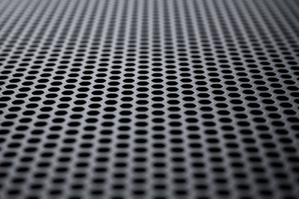istock Perspective view on a the black metal surface with regular round holes. Industrial background (abstract) 1283304150