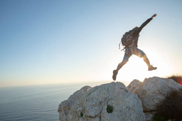 Hiker jumps across mountain ridge at sunrise