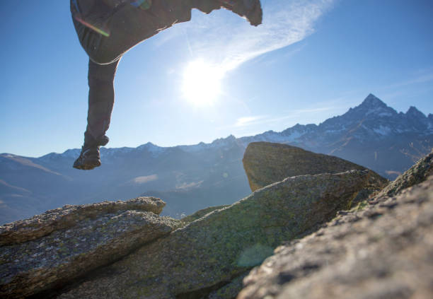 istock Hiker jumps across mountain ridge at sunrise 1283305409