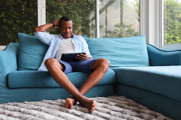 istock African American man using digital tablet while sitting on cozy sofa couch at home 1283308606