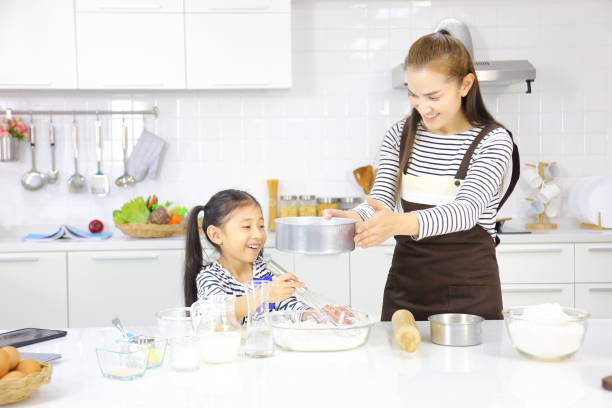 feliz madre asiática enseñando a su hija pequeña a la pan de hornear en la cocina moderna blanca mientras tamiza la harina de trigo - bun bread 7 grain bread dough fotografías e imágenes de stock