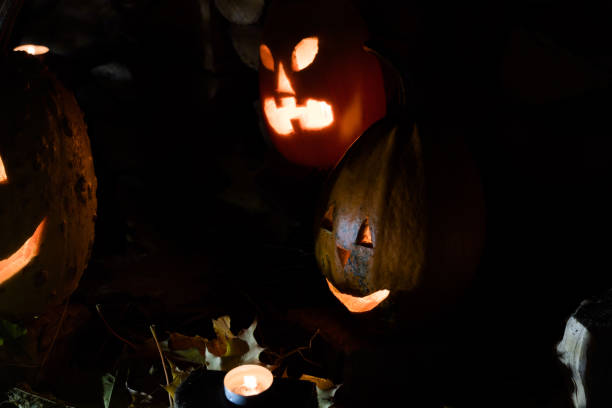 istock Two glowing pumpkins on autumn foliage with candles on Halloween night. 1283310004