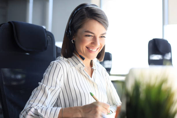 istock Beautiful smiling call center worker in headphones is working at modern office. 1283310042