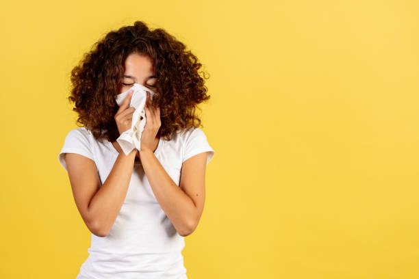Young african american woman on yellow copy space background Sickness and health care concept. Ill young african american woman with runny nose holding napkin near face, standing on yellow copy space background blowing nose photos stock pictures, royalty-free photos & images