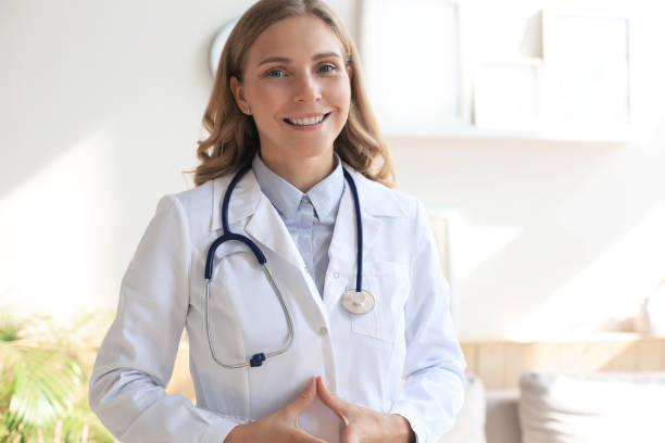 istock Happy smiling female doctor in white uniform coat and stethoscope. 1283312079