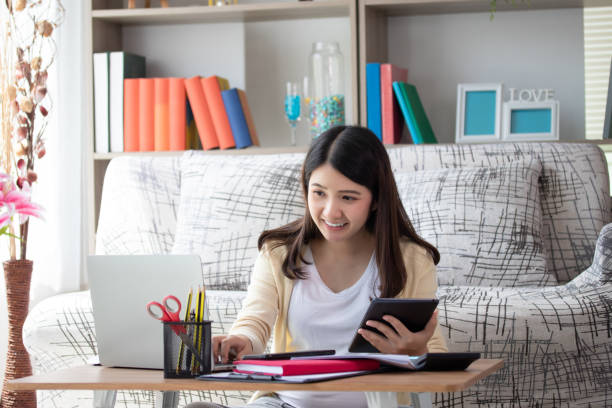 istock Beautiful young asian woman working on laptop computer while sitting smile, happy and relax at the living room. Business woman work at home concept. 1283315516
