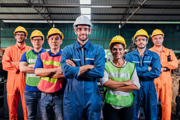 istock Successful group portrait of smart creative industry technician engineer wearing uniform and safety helmet standing and cross arms in factory station background. Industry, technician, Engineer concept 1283316581