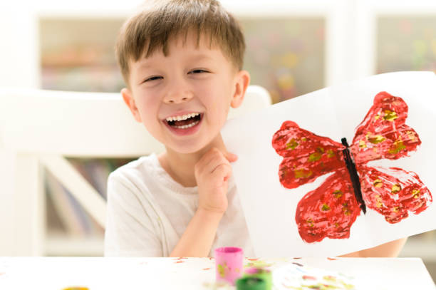 Kid Painting at Kindergarten Proud kid showing his butterfly paint craft at kindergarten homeschooling photos stock pictures, royalty-free photos & images