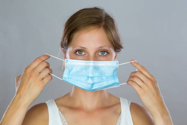 istock Young woman putting on a surgical mask in studio. 1283320683