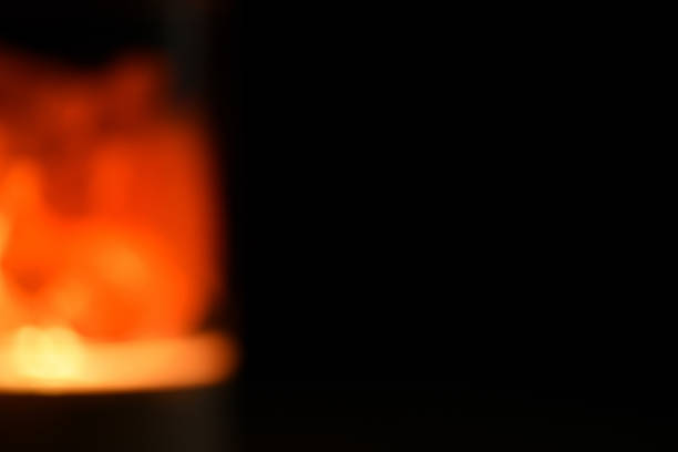 istock Orange lamp night light on a dark background, with an empty space for text on the right, close up.  The torch of the Olympic flame. Blurred background 1283321883