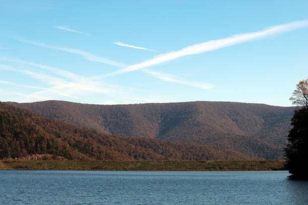 Contrails Over the Blue Ridge Mountains Airplane contrails over the Blue Ridge mountains at Switzer Lake in Virginia. The earthen dam is visible at the water line. This lake is in the George Washington National Forest and is the water supply for local communities. george washington national forest stock pictures, royalty-free photos & images