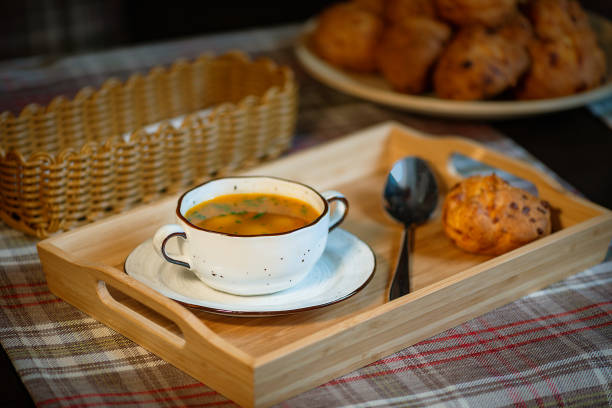 Delicious vegetarian tomato tofu soup in white cup with buns on table