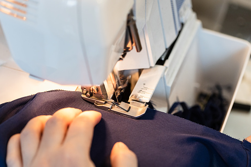 tailor overcasting the edge of fabric on serger close up at home