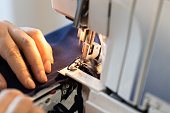 seamstress processes edge of fabric on overlocker