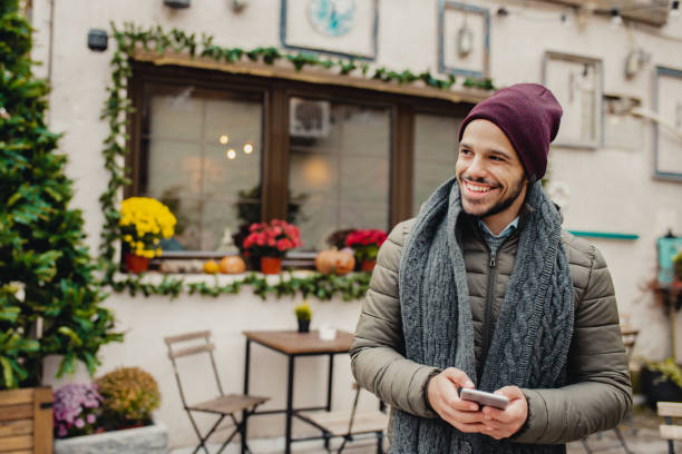 istock Young man holding smart phone outdoors during Christmas 1283328438