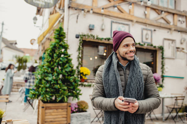 istock Young man holding smart phone outdoors during Christmas 1283328594