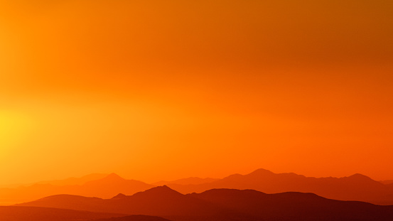 panorama of orange colored sky over some hills after a sand storm near Galup, Namibia