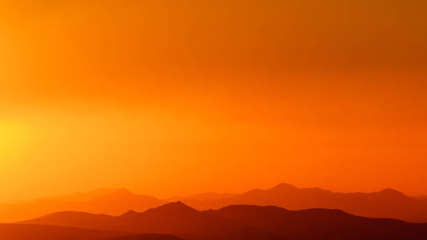 beautiful yellow and orange sky over desert hill silhouettes panorama of orange colored sky over some hills after a sand storm near Galup, Namibia namib sand sea stock pictures, royalty-free photos & images