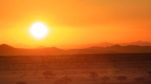 sunset over the desert in Namibia beautiful orange colored sky at sunset over desert wasteland near Galup, Namibia heat haze stock pictures, royalty-free photos & images