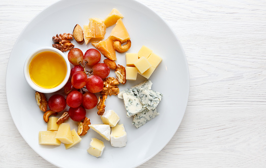 Cheese plate served with grapes and nuts. Assorted cheeses Camembert, Brie, Parmesan blue cheese, goat. Top view
